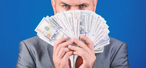 Smell of money. Easy cash loans. Man formal suit hold pile of dollar banknotes blue background. Businessman got cash money. Richness and wellbeing concept. Get cash money easy and quickly — Stock Photo, Image