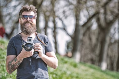 Fotoğrafçı kavramı. Adam sakallı hippi fotoğrafçı tutun vintage fotoğraf makinesi. Fotoğrafçı sakal ve bıyık amatör fotoğrafçı doğa arka plan ile. Fotoğraf çekimi ile meşgul uzun sakallı