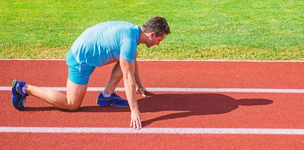 Esforçai-vos pela vitória. Corredor adulto preparar corrida no estádio. Como começar a correr. Conceito de motivação desportiva. Homem atleta corredor stand baixo início posição estádio caminho ensolarado dia. Corredor pronto para ir — Fotografia de Stock