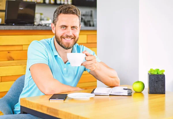 Healthy habits. Healthy man care vitamin nutrition during working day. Physical and mental wellbeing concept. Man sit eat green apple fruit. Coffee and fruit recharge energy reserve. Healthy snack