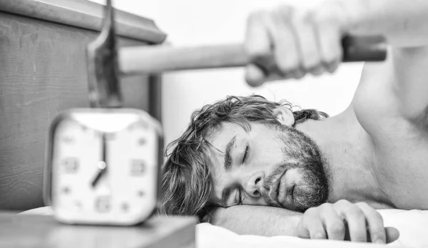 Man bearded annoyed sleepy face lay pillow near alarm clock. Guy knocking with hammer alarm clock ringing. Break discipline regime. Annoying sound. Stop ringing. Annoying ringing alarm clock
