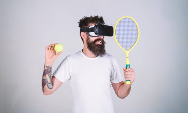 Vr gözlüklü play tenis raket ve top ile. Vr bardaklarda sakallı adam play tenis, gri arka plan. Sanal spor kavram. Gülümseyen yüzü üzerinde yenilikçi spor oyunları için modern teknolojisini kullanıyor
