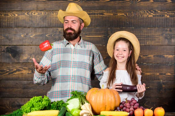 Man bearded rustic farmer with kid. Countryside family lifestyle. Farm market with fall harvest. Family farm festival concept. Family father farmer gardener with daughter near harvest vegetables