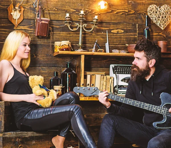 Conceito de data romântica. Casal passar noite romântica, fundo interior de madeira. Casal apaixonado em rostos relaxados desfrutar de atmosfera romântica. Homem tocar guitarra enquanto a senhora segura ursinho de pelúcia nas mãos — Fotografia de Stock