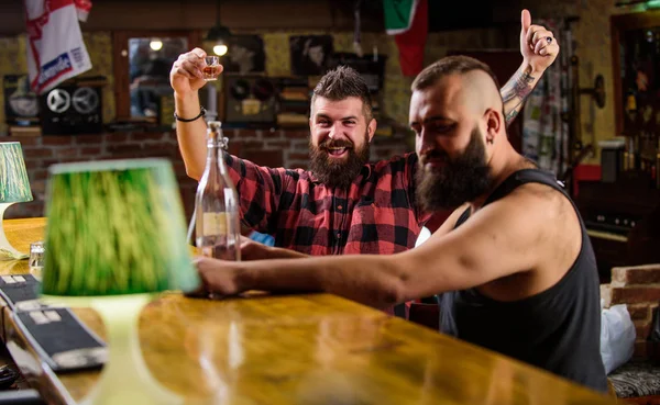 Men drinking alcohol together. Strong alcohol drinks. Alcohol addiction. Friends relaxing in pub. Men drunk relaxing at pub having fun. Hipster brutal man drinking alcohol with friend at bar counter