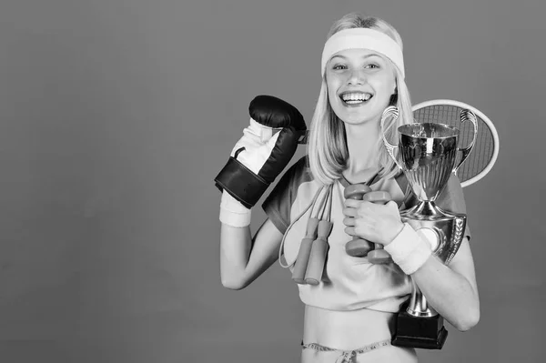 Sport shop assortment. Girl successful modern woman hold golden goblet of sport champion and equipment blue background. Sport for every day. How to find time for everything. Sport equipment store — Stock Photo, Image