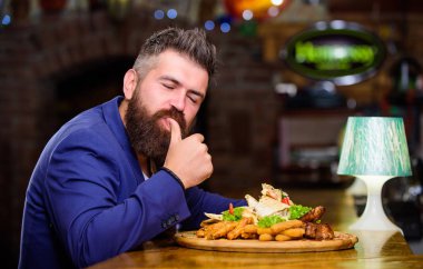 İş adamı resmi takımı restoranda oturur. Adam kızarmış patates ve balık kroket ile yemek yedi. Lezzetli yemeği hak ediyor. Afiyet olsun. Yüksek kalorili atıştırmalık. Lezzetli yemek. Zor bir günün ardından rahatla
