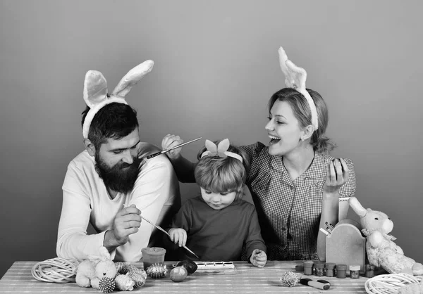 Miembros de la familia pintando huevos sobre fondo azul —  Fotos de Stock