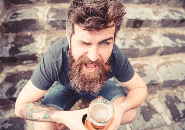 生ビールと残りの部分を持つ男。屋外ビールを飲む陽気な顔で流行に敏感。ドラフト ビールのコンセプトです。おしり、石階段背景上に座っている間保持しているビールをひげと口ひげを持つ男 — ストック写真