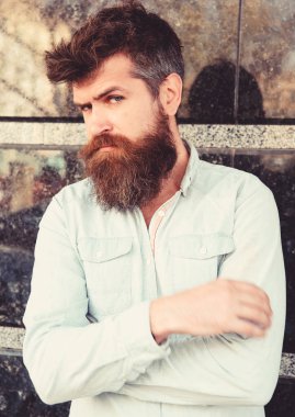 Erkeklik kavramı. Adam şüpheli görünüyor. Tousled saçlı hippi tutun kollar göğüs üzerinde geçti. Sakal ve bıyık düşünceli, dalgın yüzünde siyah mermer zemin üzerine olan adam