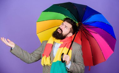 Hava tahmini kavramı. Adam hipster tutun renkli şemsiye sakallı. Yağmur gibi görünüyor. Yağmurlu gün ulaşmak zor olabilir. Kara gün için hazırlanmış. Kaygısız ve olumlu. Yağmurlu bir gün zevk