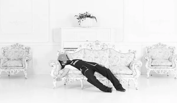 피곤된 남자 직장에서 짧은 낮잠을 즐기는입니다. 움직이는 피아노와 빈티지 가구와 화이트 룸에 소파에 누워 수염 — 스톡 사진