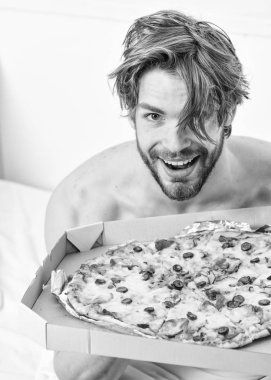 Adam, kahvaltıda pizza seviyor. Seksi erkek yatakta yatarken pizza yemek. Bir yatağa evde döşeme sırasında tembel kaslı adam yeme pizza portresi. Evde pizza.