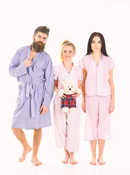 Flickor med skäggiga macho i pyjamas och morgonrock i morgon, isolerade vit bakgrund. Mannen med skägg, Söt blond och brunett flickor med leksak Björn bara vakna upp i morgon. Sömnig morgonen koncept — Stockfoto