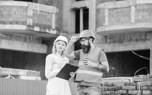 Woman engineer and builder communicate at construction site. Discussing plan. Construction team communication concept. Relationships between construction clients and participants building industry
