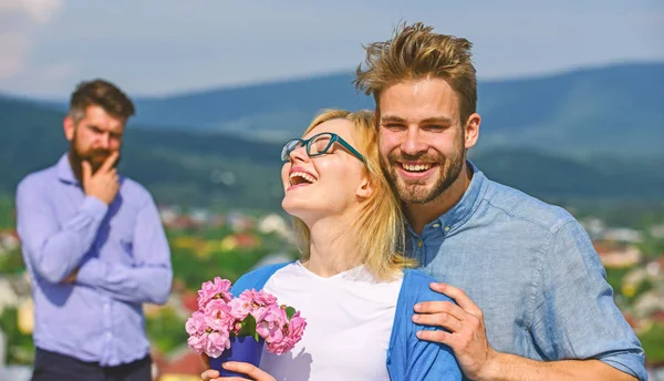 Lovers hugs outdoor flirt romance relations. Couple romantic date lovers bouquet flowers. Infidelity concept. Couple in love dating while jealous bearded man watching wife cheating him with lover — Stock Photo, Image