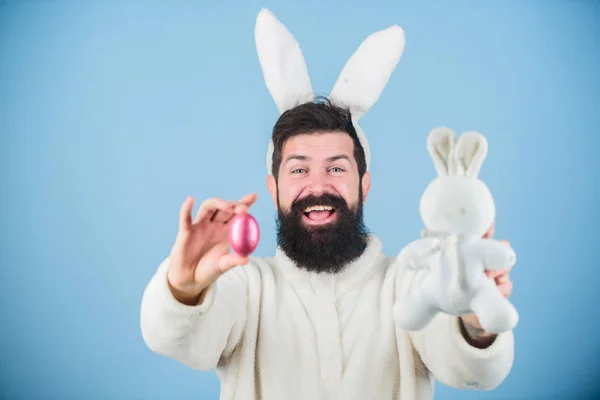 Partilhar um ovo abençoado. Coelho da Páscoa entregando ovos coloridos. Celebração de férias de primavera. Hipster com longas orelhas de coelho segurando a lebre poedeira. Homem barbudo com brinquedo de coelho e ovo de Páscoa — Fotografia de Stock