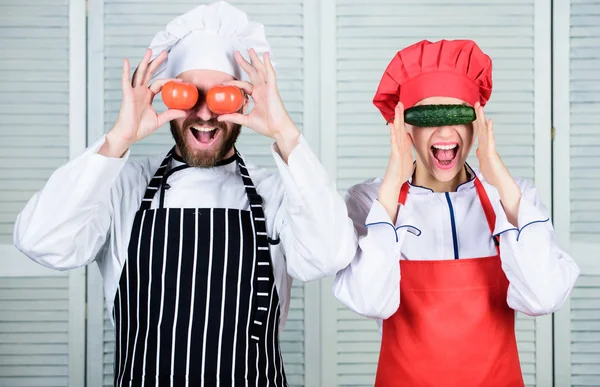 Cooking together is fun. Menu for our family. Go vegan. Organic nutrition. Vegan family. Man and woman chef hold vegetables having fun. Couple play with ingredients for vegan dish. Cooking vegan meal