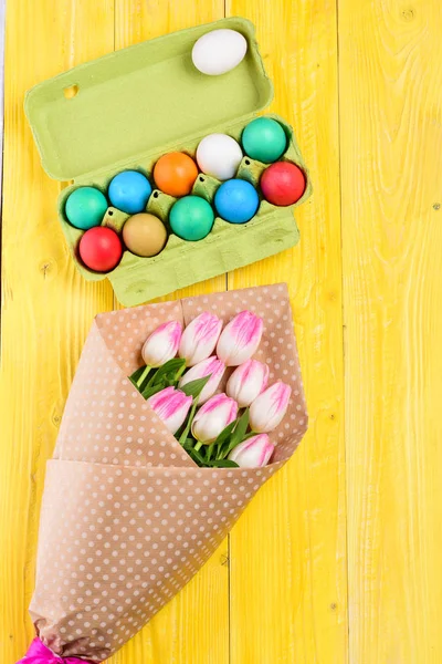 Spring holiday. Holiday celebration, preparation. painted eggs in egg tray. Tulip flower bouquet. Healthy and happy holiday. Happy easter. Egg hunt. Easter decor