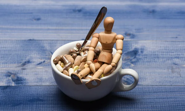 Wooden human dummy near cup full pills and tablets. Vitamin cocktail. Health problem. Immunity care and medicine vitamins. Mixing medicines. Fast treatment. Take medicine concept. Medicines dose