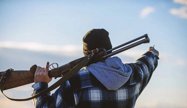 Guy Hunter pasa tiempo libre cazando. Hombre tipo brutal guardabosques en el fondo de la naturaleza sombrero. Caza masculina hobby concepto de ocio. Brutalidad y masculinidad. Hunter llevar pistola de rifle en el hombro vista trasera — Foto de Stock