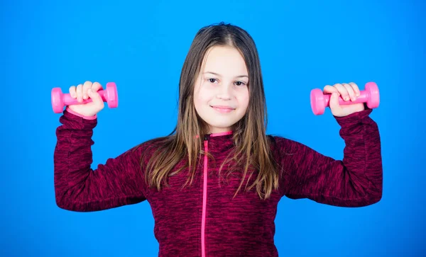 Levantamiento de pesas para músculos. Actividad infantil. Dieta fitness para la salud energética. El entrenamiento de una niña pequeña tiene mancuerna. Éxito deportivo. Niño deportista feliz con barra. actividad deportiva. actividad en interiores — Foto de Stock