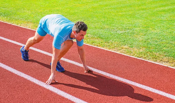 Sporttipps vom Profi-Läufer. Mann Athlet Läufer stehen niedrige Startposition Stadionweg. Bemüht euch um den Sieg. Läufer bereit für den Start. Erwachsene Läufer bereiten Rennen im Stadion vor. Wie man mit dem Laufen anfängt — Stockfoto