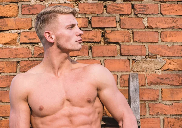 Attractive and confident. Sexy torso sportsman. Man muscular athlete lean on wall relaxed. Strong muscles emphasize masculinity sexuality. Man muscular chest naked torso stand brick wall background