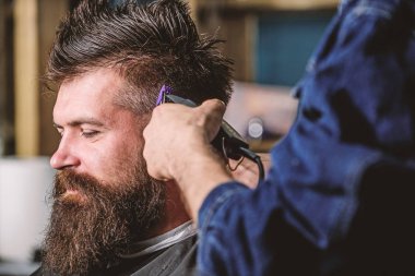 Berber kavramı. Eller berberin saç kesme makinesi ile kapatın. Hippi saç modeli almak istemci sakallı. Kuaför saç kesme makinesi ile çalışır. Sakallı salonların sandalye, koyu arka plan