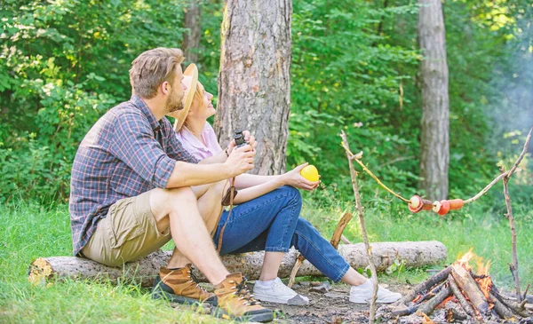 Couple relaxing sit on log having snacks. Hike picnic date. Family enjoy romantic weekend in nature. Pleasant picnic or romantic date nature background. Couple romantic date near bonfire in forest — Stock Photo, Image