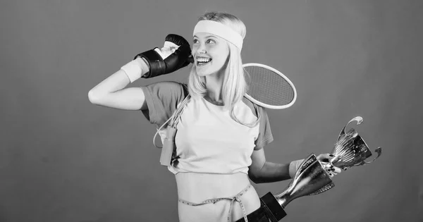 Deporte para cada día. Cómo mantenerse en forma para siempre. Tienda de equipos deportivos. Surtido de tiendas deportivas. Chica alegre éxito mujer moderna celebrar copa de oro del campeón del deporte y el equipo de fondo rojo — Foto de Stock