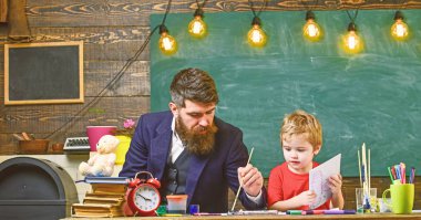 Çizim ders kavramı. Öğretmen sakal, baba ve küçük oğul çizerken, sınıfta oluşturma, kara tahta arka plan ile. Çocuk ve resim, çizim meşgul yüzleri öğretmen