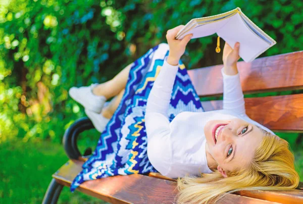 Interessant boek. Vrouw doorbrengen vrijetijdsbesteding met boek. Lady lachend gezicht geniet van rust. Meisje buiten lezen terwijl u ontspant op Bank. Meisje lag Bank park ontspannen met een boek, groene natuur achtergrond — Stockfoto