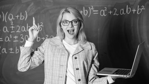 Educational site for teachers. Educator smart clever lady with modern laptop searching information chalkboard background. Online schooling concept. Woman wear eyeglasses holds laptop surfing internet Stock Image