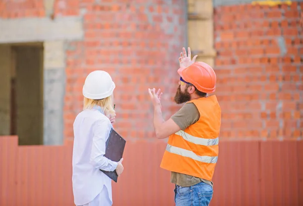 Construction project management. Building industrial project. Discuss progress project. Construction industry concept. Woman engineer and bearded brutal builder discuss construction progress