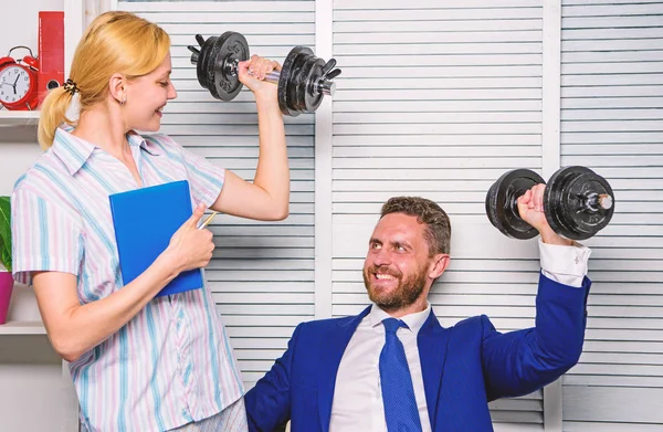 Healthy habits in office. Man and woman raise heavy dumbbells. Strong powerful business strategy. Good job concept. Boss businessman and office manager raise hand with dumbbells. Strong business team