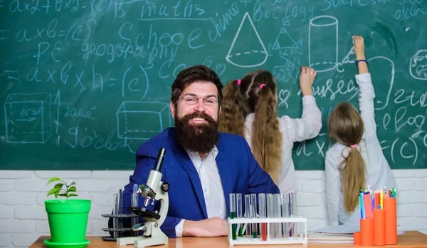 Man bearded teacher work with microscope and test tubes in biology classroom. Explaining biology to children. How to interest children study. Fascinating biology lesson. School teacher of biology