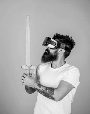 Hipster ciddi bir yüz üzerinde sanal gerçeklik oyun oyun keyfini çıkarın. Oyun kavramı. Adam kafa monte ekran ile kılıç tutan, dövüş Vr gözlük, açık mavi renkli sakallı Vr. adam oyunu oyna