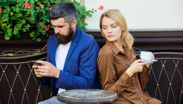 Morning starts with coffee and Internet. woman and man with beard relax in cafe. First meet of girl and man. Couple in love has problems. Morning coffee. bearded hipster use phone, girl drink coffee