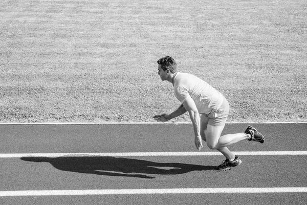 Muž sportovec běžec shodit z počáteční pozice stadion cestu slunečný den. Běžec sprintu na stadionu. Běžec zachycena v pohybu, těsně po začátku závodu. Jak se rozběhnou. Zvýšení rychlosti koncept — Stock fotografie