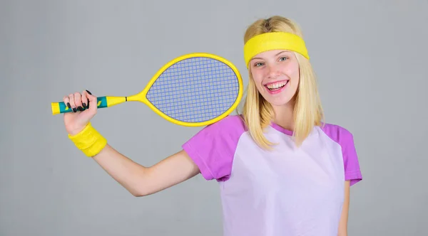 Tennis club concept. Girl adorable blonde play tennis. Sport for maintaining health. Active leisure and hobby. Athlete hold tennis racket in hand on grey background. Tennis sport and entertainment — Stock Photo, Image
