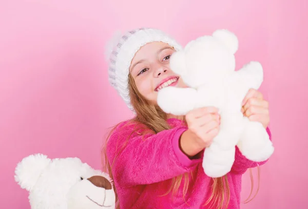 Ребенок маленькая девочка игривая держать плюшевую игрушку плюшевого медвежонка. Почему дети любят мягкие игрушки. Игрушки каждый ребенок мечтает. Малышка играет с мягким игрушечным плюшевым мишкой на розовом фоне. Концепция счастливого детства — стоковое фото