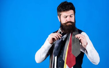 Beyefendinin Kılavuzu. Nasıl doğru kravat seçmek için. Klasik tarzı. Nasıl boyun gömlek ve takım elbise ile maç. Sakallı adam hipster kaç Kravatlar mavi arka plan üzerinde tutun. Kravat seçme sakallı adam