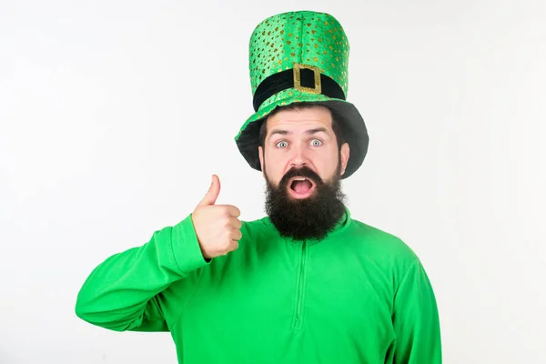 Happy saint patricks day. Hipster in leprechaun hat and costume keeping mouth open. Bearded man celebrating saint patricks day. Irish man with beard wearing green. Thumbs up for saint patrick Stock Picture