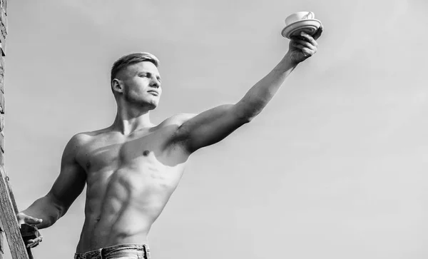 Man muscular athlete bodybuilder offers you coffee. Macho muscular chest naked torso hold mug of fresh coffee blue sky background. Waiter bare chest hold coffee cup. Sexy torso attractive waiter — Stock Photo, Image