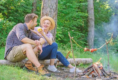Çift rahatlatıcı aperatifler sahip oturum açma otur. Aile doğada romantik hafta sonu keyfini çıkarın. Kıza teklifler elma onlar kavrulmuş gıda bekleyen yemek. Piknik yemeği ateşte kavurma. Yemeğimi yerim. Piknikte yemek