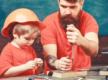 Çocuk, Çocuk koruyucu kask babamla tornavida kullanmayı öğrenme içinde meşgul. Baba, üst araç tornavida kullanmak için küçük oğlu öğretim sakallı. Tamirci ve atölye kavramı
