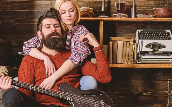 Señora y hombre con barba en caras de ensueño abrazos y toca la guitarra. Pareja en madera vintage interior disfrutar de la música de guitarra. Pareja enamorada pasar una velada romántica en un ambiente cálido. Concepto romántico de noche — Foto de Stock