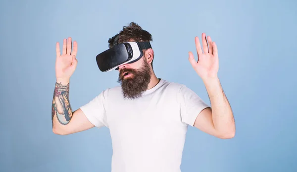 Homem com barba em óculos VR, fundo azul claro. Hipster no rosto ocupado explorando a realidade virtual com gadget moderno. Conceito de dispositivo VR. Cara com cabeça montada exibir interagir em realidade virtual — Fotografia de Stock