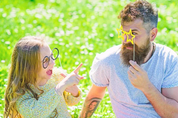 Vader en dochter zit op gras op grassplot, groene achtergrond. Kind en vader poseren met eyeglases foto stand kenmerk terwijl het spreken. Communicatieconcept. Familie doorbrengen vrijetijdsbesteding buitenshuis — Stockfoto